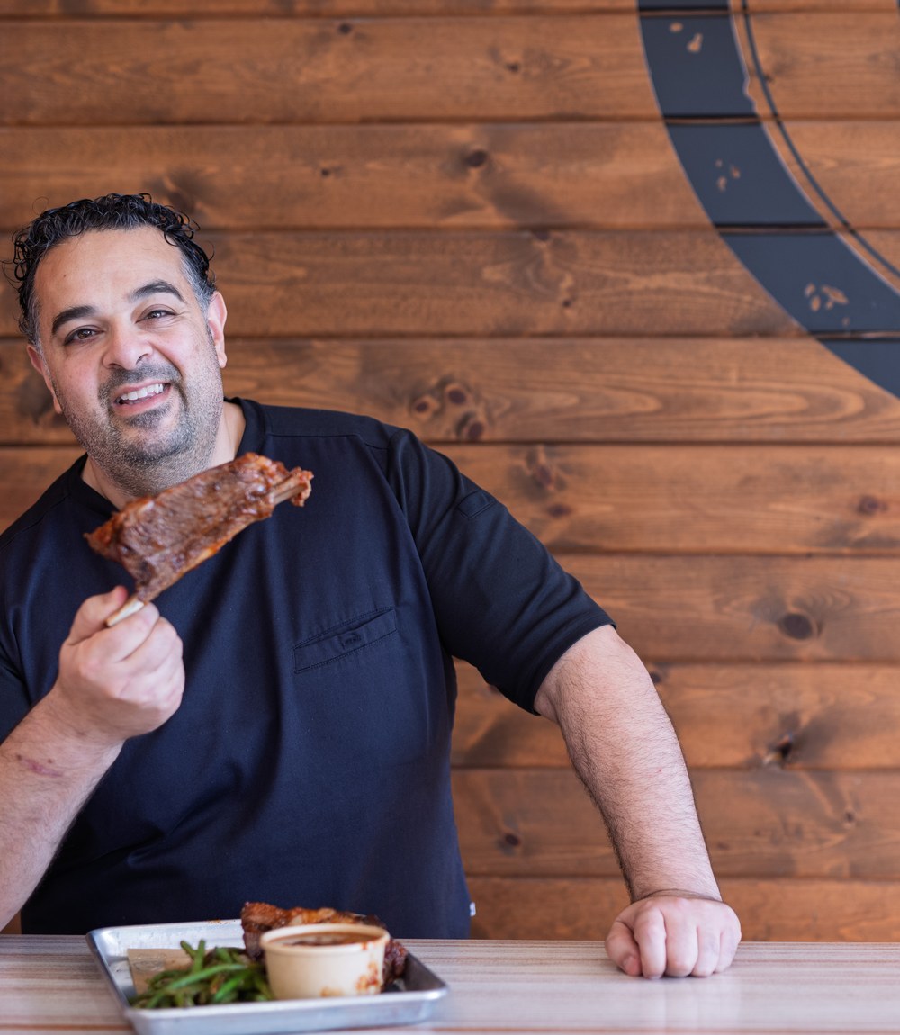 Chef Essi Tadrus, founder of Southern Luv BBQ, holding a rack of pecan-smoked ribs