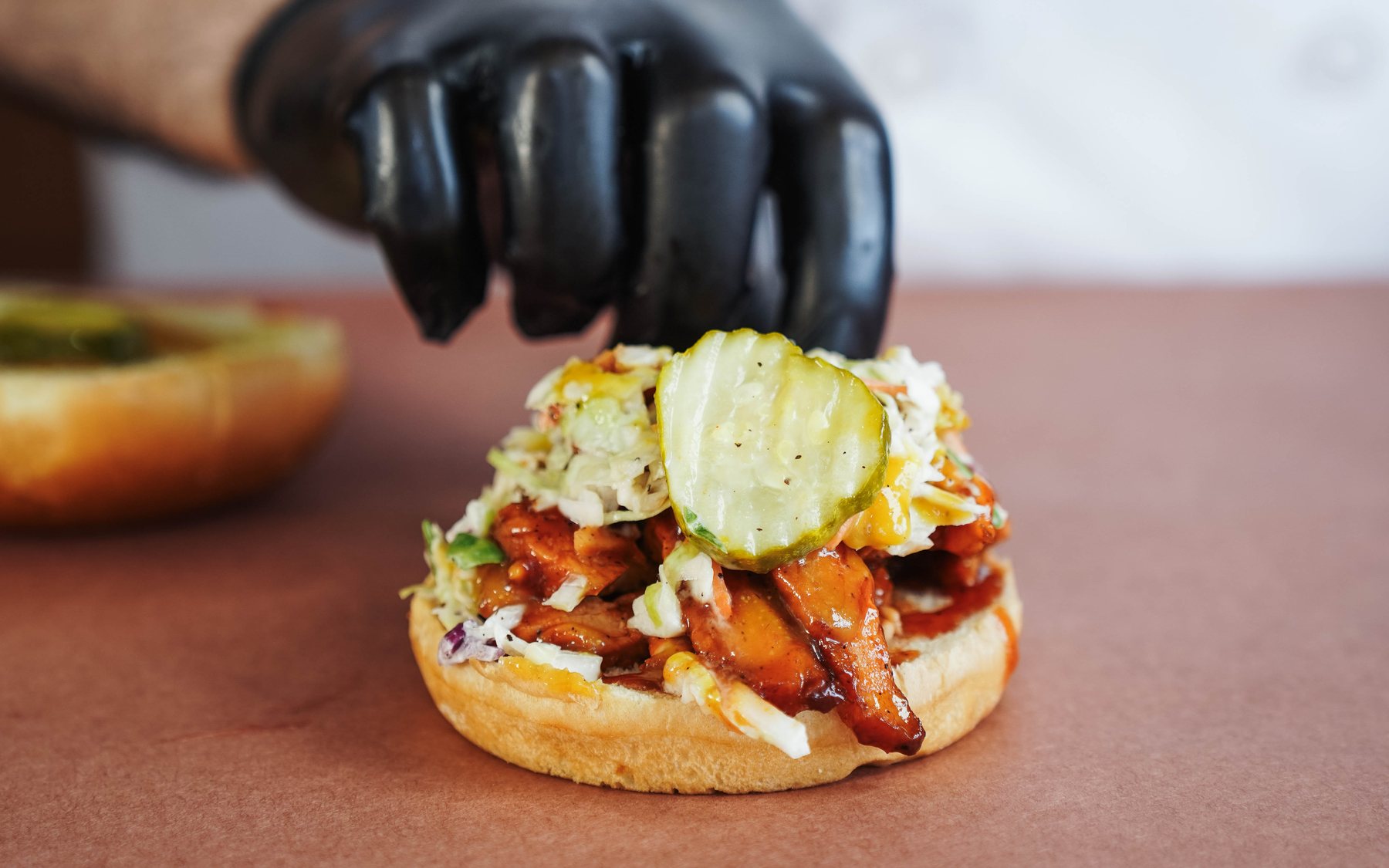 A Southern Luv BBQ sandwich being finished by hand